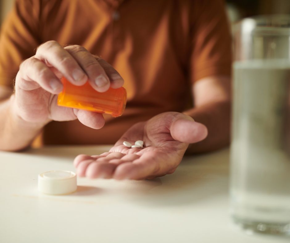 Persona tomando antiinflamatorios con un vaso de agua para aliviar el dolor musculoesquelético